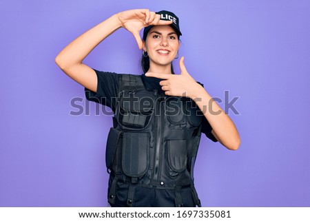 Young police woman wearing security bulletproof vest uniform over purple background smiling making frame with hands and fingers with happy face. Creativity and photography concept.
