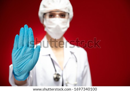Pandemic doctor is showing stop sign on red background.