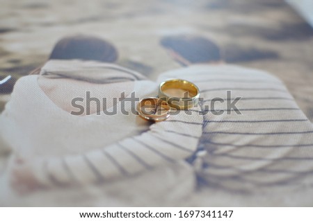 Engagement wedding rings on canvas texture with printed photograph of hugging couple.