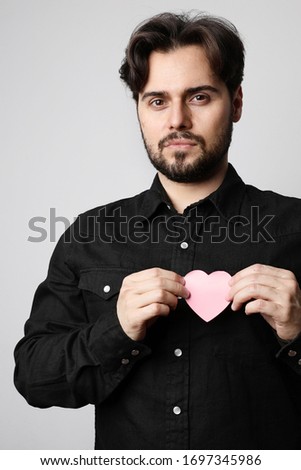 Vertical studio portrait of bearded man holding a heart sign. Relationship concept.