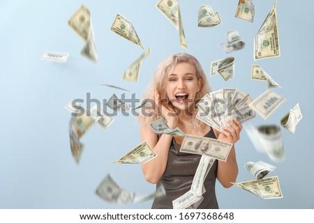 Beautiful young woman with flying money on grey background
