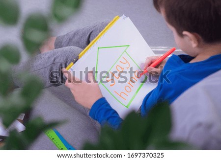 child draws a picture at home with the words stay home. Coronavirus concept