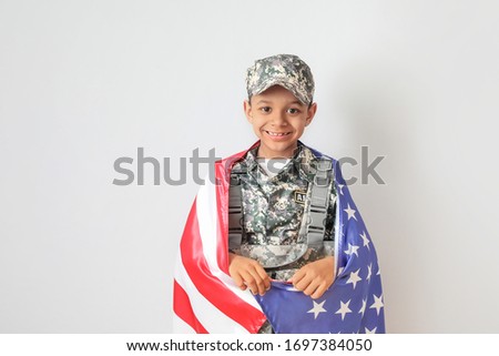 Little African-American soldier with USA flag on light background