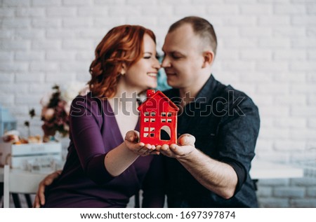 Happy couple holding their dream house in their hands, real estate and home insurance concept