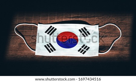 Korea, South National Flag at medical, surgical, protection mask on black wooden background. Coronavirus Covid–19, Prevent infection, illness or flu. State of Emergency, Lockdown