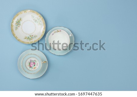 Vintage china teacups on pale blue background with space for copy Royalty-Free Stock Photo #1697447635