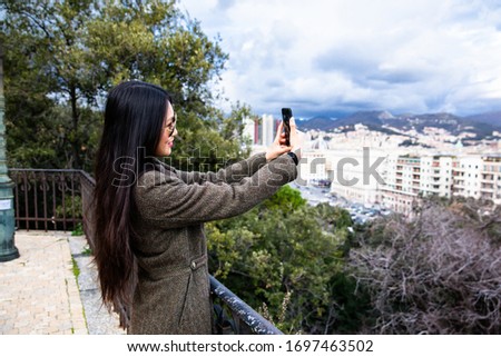 Happy asian girl using phone and traveling in Genoa,Italy