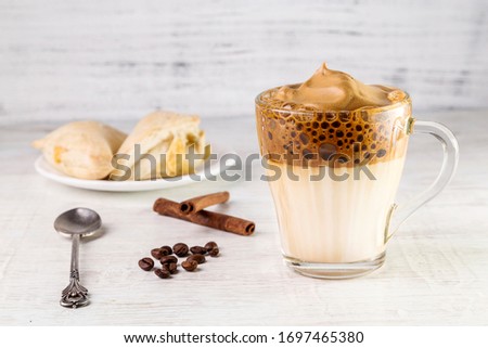 Iced Dalgona Coffee, fashionable fluffy creamy whipped coffee on a light background.