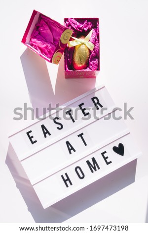 Easter at home for coronavirus, celebrating easter at home conceptual image due to covid 19 pandemia, a chocolate golden egg against a textbox with easter at home message,