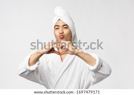 Beauty, spa and leisure concept. Silly and funny cute asian man with bath towel on head and bathrobe, pouting and make kissing face, show heart sign, express love and sympathy, white background