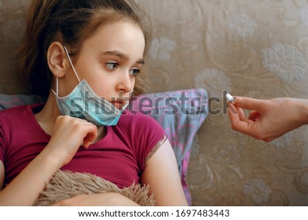 A girl in a protective mask became infected with a coronovirus, quarantine, a doctor gives a pill, a sad child, Covid-19 virus, airborne droplets, a worldwide pandemic, flu, treatment for the disease