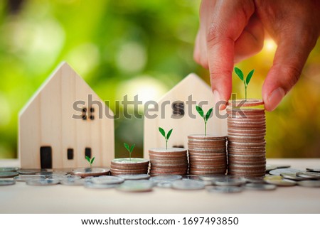 Financial and Save Money concept to buy house. Hand putting stack coins for growing with sunlight bokeh background and tree growing on coin.