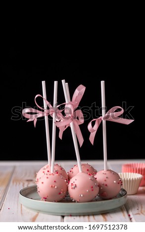 Cake pops in pink cream lie on a beautiful plate. Delicious close-up dessert. Tasty food