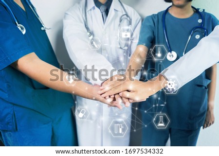 Medical and healthcare nurses and doctors working to together fighting pandemic of corona virus disease, standing around with hands on top each other forming strong bond, motivation and coordination   Royalty-Free Stock Photo #1697534332