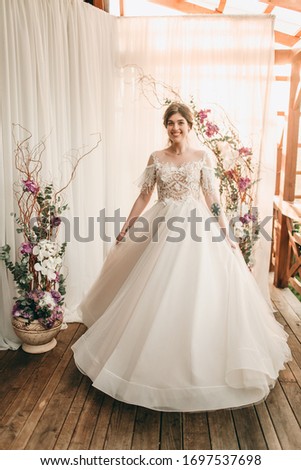 Young happy bride dancing near photophone, on white background. Restaurant, wedding celebration, photo shoot, portrait
