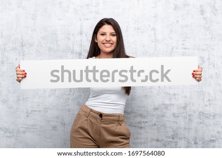 young pretty woman holding a banner against grunge wall
