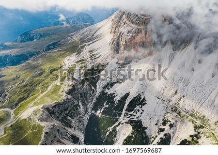 Italian Dolomites, Tre Cime - Rifugio Lavaredo - stony road around Tre Cime .Peak in the clouds. Aerial shot.