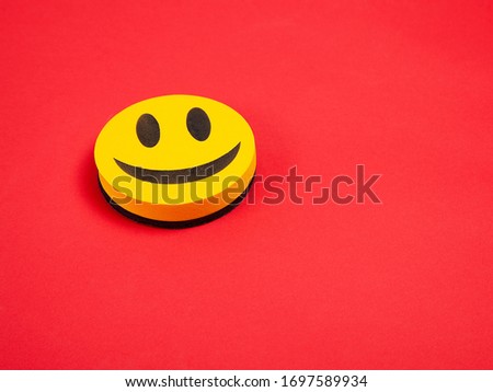 Yellow three-dimensional smile on a red background. Funny look. Space for text. Happiness, joy, luck, success in business.