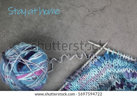 Knitting, ball of yarn and knitting needles on a dark surface with place for text. Inscription Stay at home.
Global pandemic Covid -19 prevention. Quarantine and warning, attention.