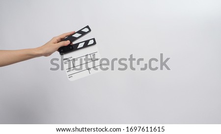 Hand is holding small clapper board on white background.