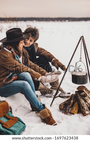 Loving couple on a ranch are sitting near a fire in the winter, NOISE EFFECT ON PHOTOS