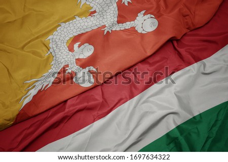 waving colorful flag of hungary and national flag of bhutan. macro