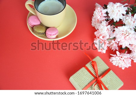Mothers day or women's Day concept - box with a gift a beige cup of cappuccino beautiful white-pink aster flowers on a red background. good morning. greeting card. view from above. save space cookies