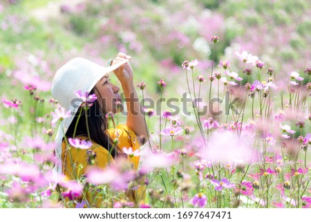 Traveler or tourism Asian women standing and chill  in the cosmos flower field in vacations time.  People  freedom and relax in the spring  meadow.  Lifestyle Concept