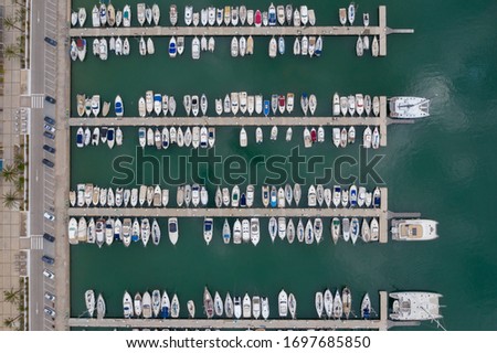 Aerial drone top down photo of yachts and sailboats docked in a big harbour port in a city south of Barcelona, Spain