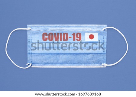 Medical mask and text or inscription Covid-19. Coronavirus pandemic concept. Flag of Japan.
