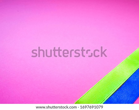 On a pink background, two satin ribbons of bright yellow and blue . Decor