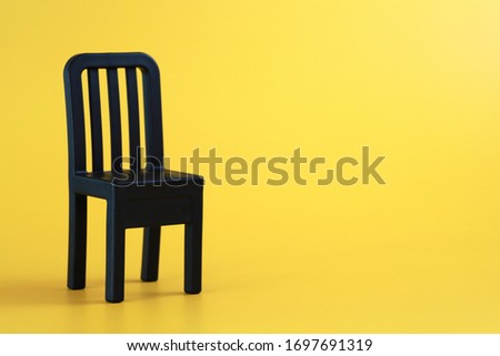 A black mini display chair on yellow background