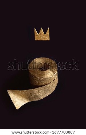 Gold toilet paper with a crown on a black background. A concept on the topic of coronavirus and pandemic.