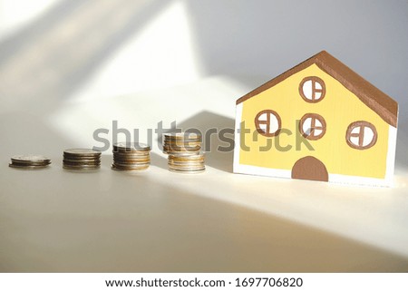toy house and stacks coins as symbol of Finance and mortgage, saving money for a house concept. real estate for family. own house under sunlight