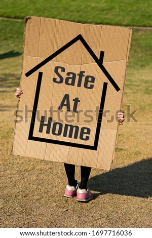 Little girl holding a sign showing the symbol of the recommendations to be detained at home to prevent the corona virus infection.