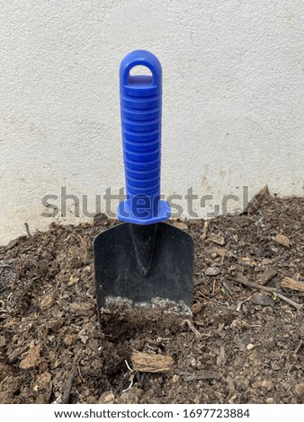 Digs soil with a blue shovel in the garden