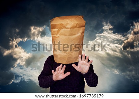 Man with a package on his head on a stormy sky background. The man is looking for a blind road