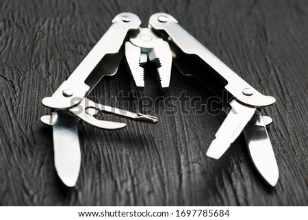 Multi-functional tool on a black textural background.