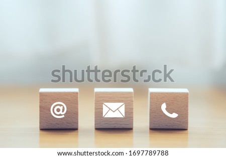 contact us icon (phone, email, mail ) on wood cube, customer service and support for self quarantine business working at home for Coronavirus or virus preventing concept Royalty-Free Stock Photo #1697789788