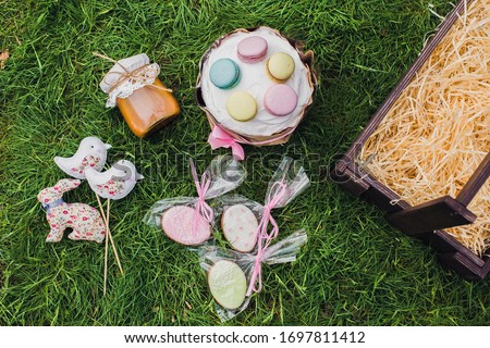 Easter dishes on the grass. Contents: Easter cake, gingerbread cookies decorated with icing, a jar of caramel, handmade toys: rabbit, birds