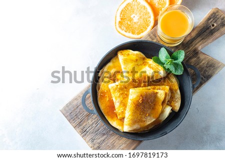 Crepes with Orange Sauce in a cast iron pan. Traditional French crepe Suzette with orange sauce. Flat lay, top view Royalty-Free Stock Photo #1697819173