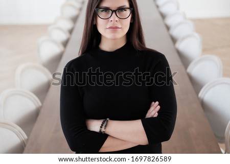 Pleased business woman with crossed arms looking at the camera. meeting table on the background. close-up.
