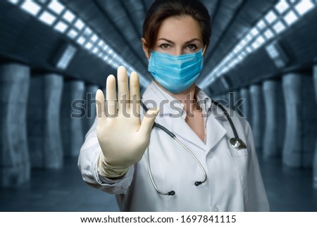 The concept of Stop Virus. Doctor shows prohibiting sign with hand on blurred background.