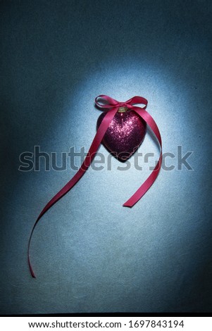 Beautiful pink heart with glitter and bow , spotlight effect on dark wallpaper, christmas background
