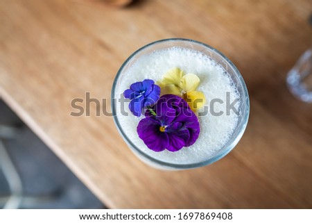 Glass of milkshake isolated with flowers on wood background from top view