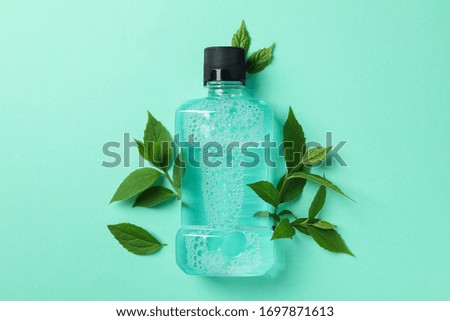Mouthwash and leaves on mint background, space for text Royalty-Free Stock Photo #1697871613