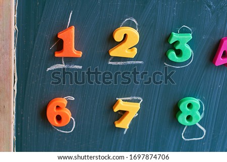 Learning numbers on a blackboard with colorful magnets and handwriting on blackboard during homeschooling. Quarantine lifestyle concept.