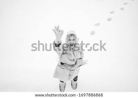 Funny face. Beautiful happy laughing young woman wearing winter hat gloves and scarf covered with snow flakes. Winter woman portrait outdoor