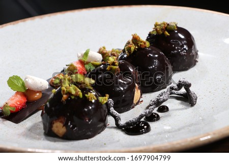 Tasty profiteroles with cream and chocolate glaze on a plate
