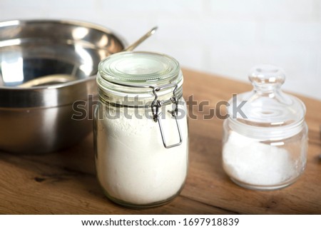Jars with wheat flour, salt and a steel bowl on a kitchen table. Preparation for cooking. Knead the dough Royalty-Free Stock Photo #1697918839